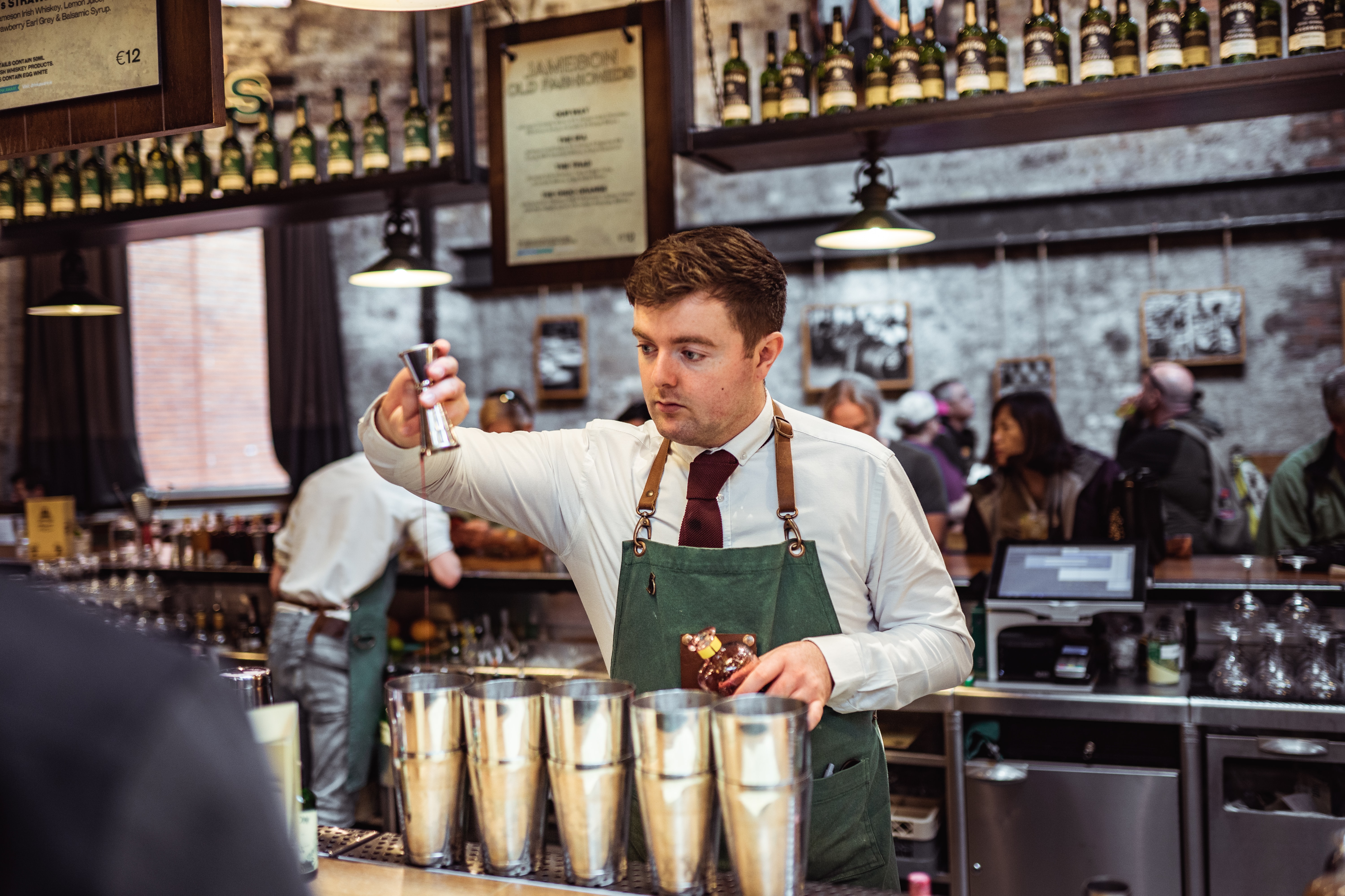 An Irish Bartender with bar supplies, pouring alcohol into a drink